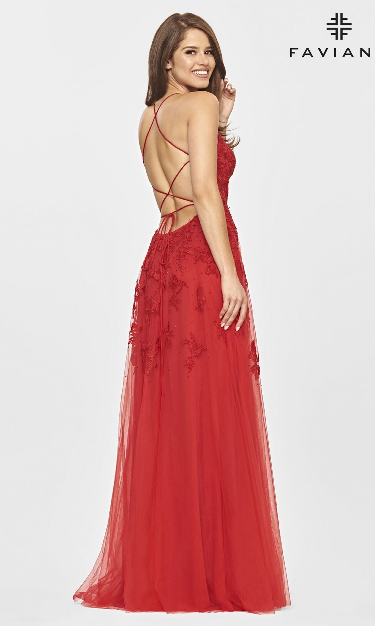 Woman in a red Faviana Strappy-Back Long Lace A-Line Prom Dress with lace details and crisscross open back, standing and smiling over her shoulder. This formal gown exudes elegance—perfect for prom.